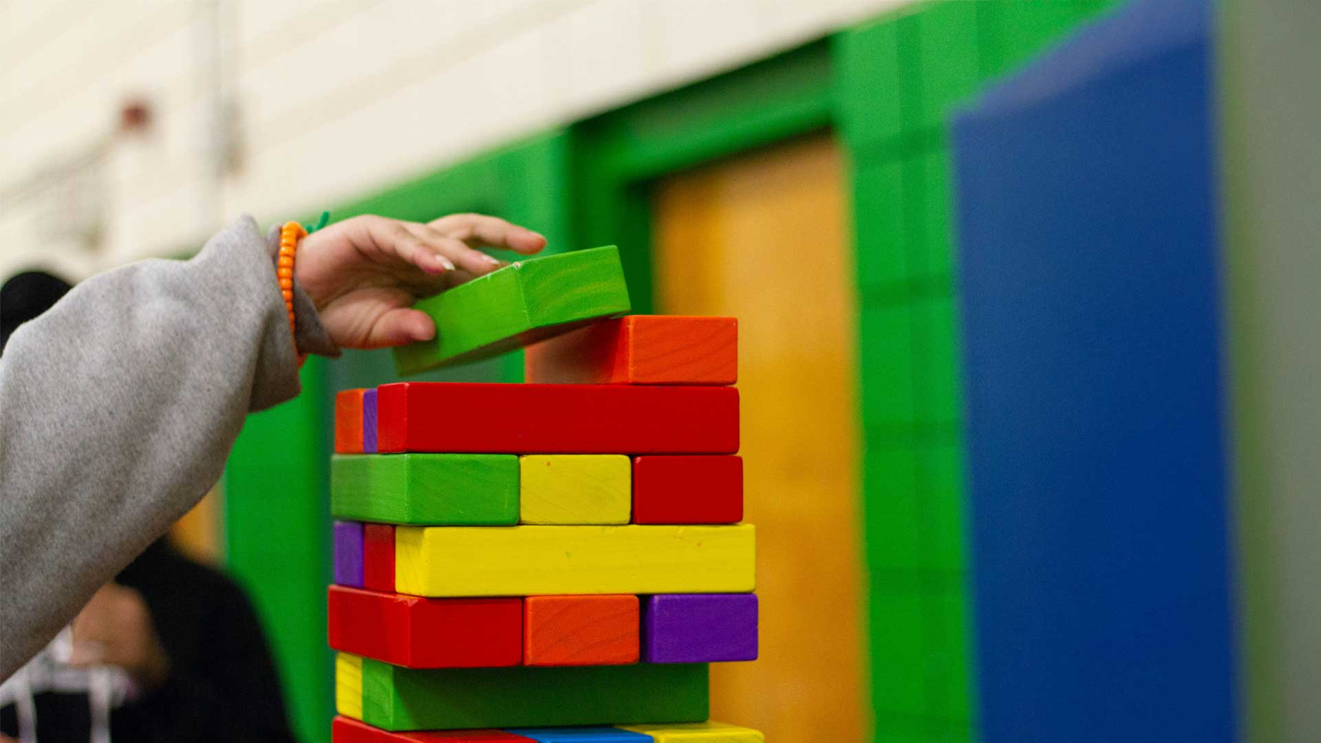 mano di un bambino che costruisce una torre con mattoncini colorati